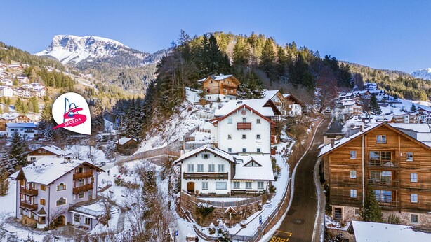 Un village de montagne enneigé, avec ses maisons traditionnelles en bois, une station de ski et une vue dégagée sur les montagnes environnantes.