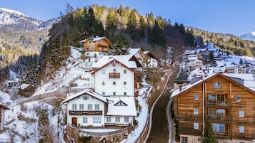 Ein verschneites Bergdorf mit traditionellen Holzhäusern, einem Skigebiet und freiem Blick auf die umliegenden Berge.