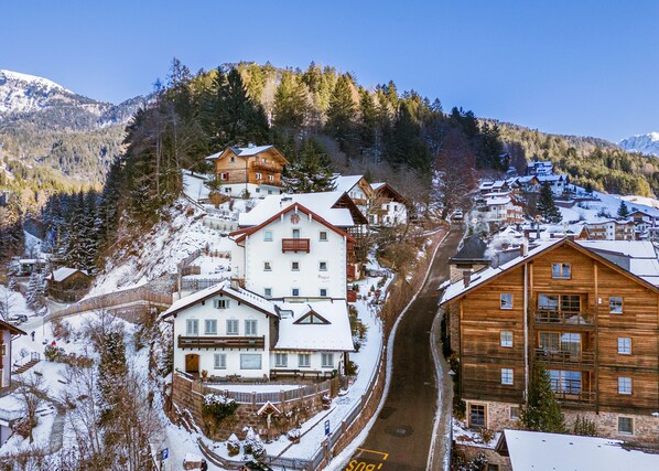 A snow-covered mountain village with traditional wooden houses, a ski resort, and a clear view of the surrounding mountains.