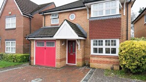 A two-story house with a red garage door, a small porch, and a well-maintained garden. - 3 bed house for up to 6 people In Cardiff, Wales (Cardiff)
