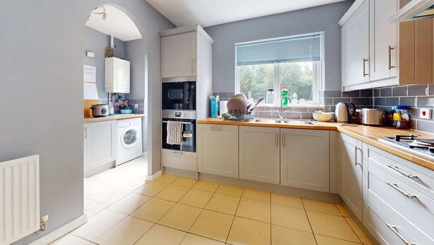 A modern kitchen with white cabinets, a built-in oven, a washing machine, and a window with a view. - 3 bed house for up to 6 people In Cardiff, Wales (Cardiff)