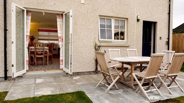 Una casa con patio, que incluye una mesa, sillas, una ventana y una puerta.