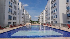 A swimming pool surrounded by white buildings with balconies and air conditioning units. - Covenas Refugio de Familia junto al Mar (Coveñas)
