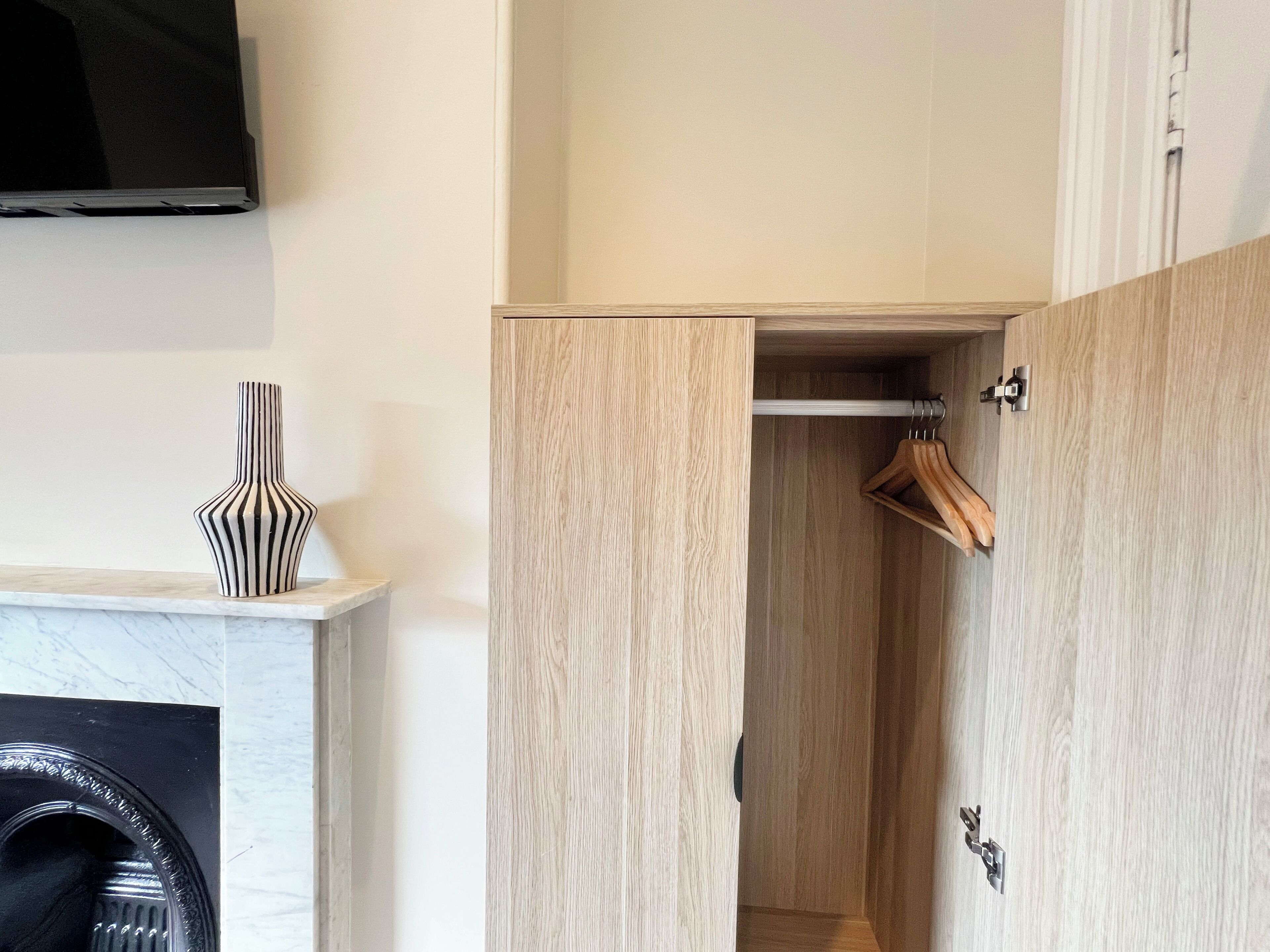 Een moderne kamer met een houten garderobe, een kapstok en een marmeren open haard.