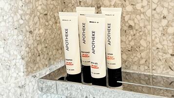 Una estantería en el baño con cuatro botellas de productos para el cuidado de la piel Apotheke.