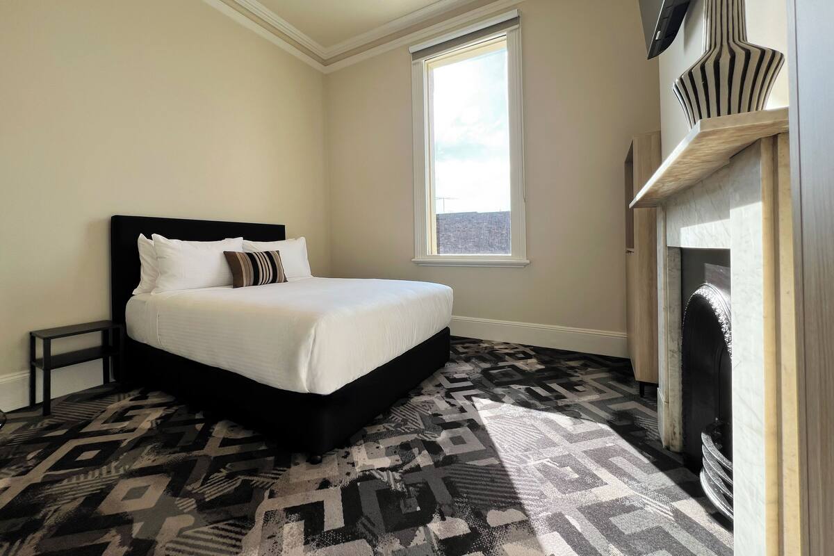A bedroom with a bed, a window, and a fireplace.