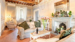 A cozy living room with a fireplace, a chandelier, and a comfortable seating area.