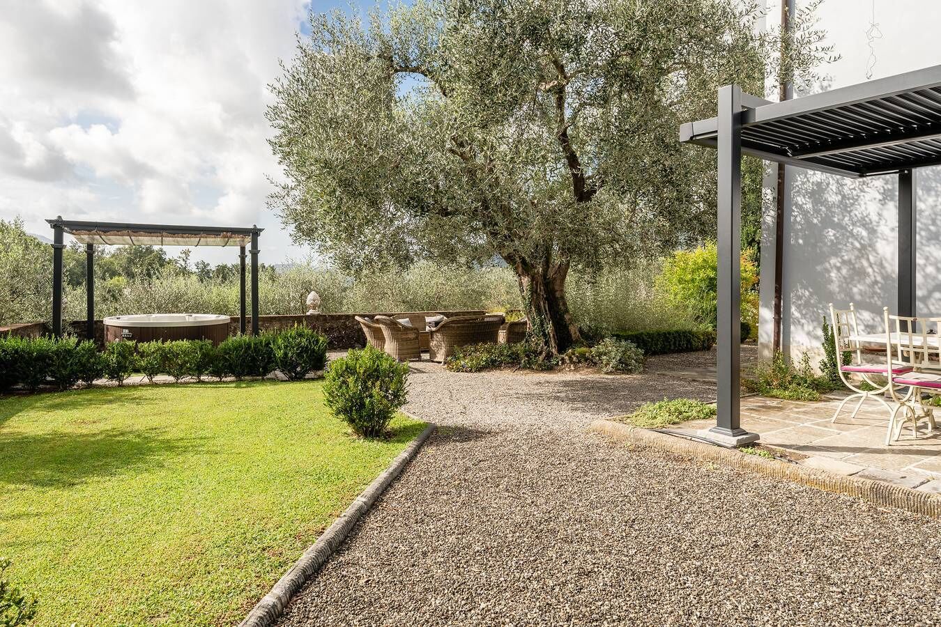 Ein Garten mit einer Pergola, einer Sitzecke und einem Whirlpool.