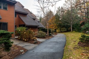 A residential street with a house featuring a sloped roof and a pathway leading to it. - Family-friendly condo with amenities minutes from StoryLand & ski mountains! (Bartlett)