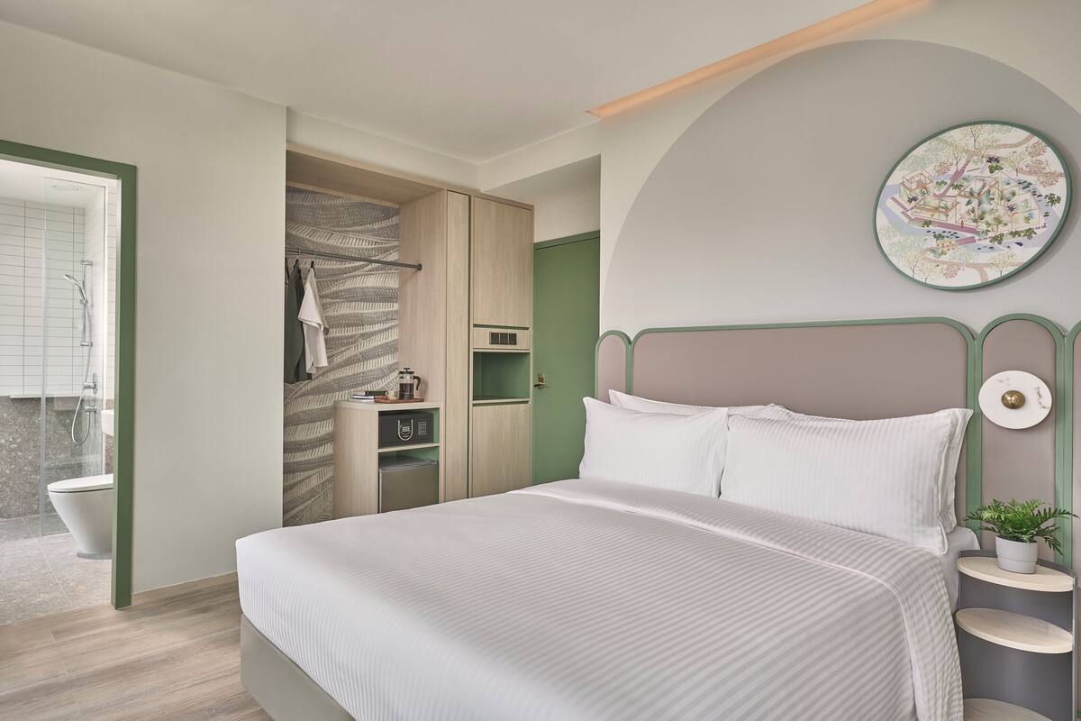 Une chambre à coucher moderne avec un grand lit, un dressing, un espace douche et une œuvre d’art accrochée au mur.