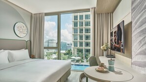 Habitación de hotel con una cama grande, una mesa de comedor, vista a la ciudad y una piscina.