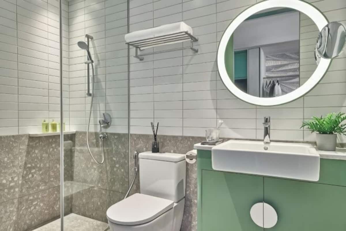 A modern bathroom with a glass-enclosed shower, a toilet, a sink, and a mirror.