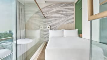 Un dormitorio moderno con una cama grande, un separador de vidrio, vistas a la ciudad y una pared con estampado.