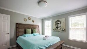 A bedroom with a wooden bed, a bench, and a large window.