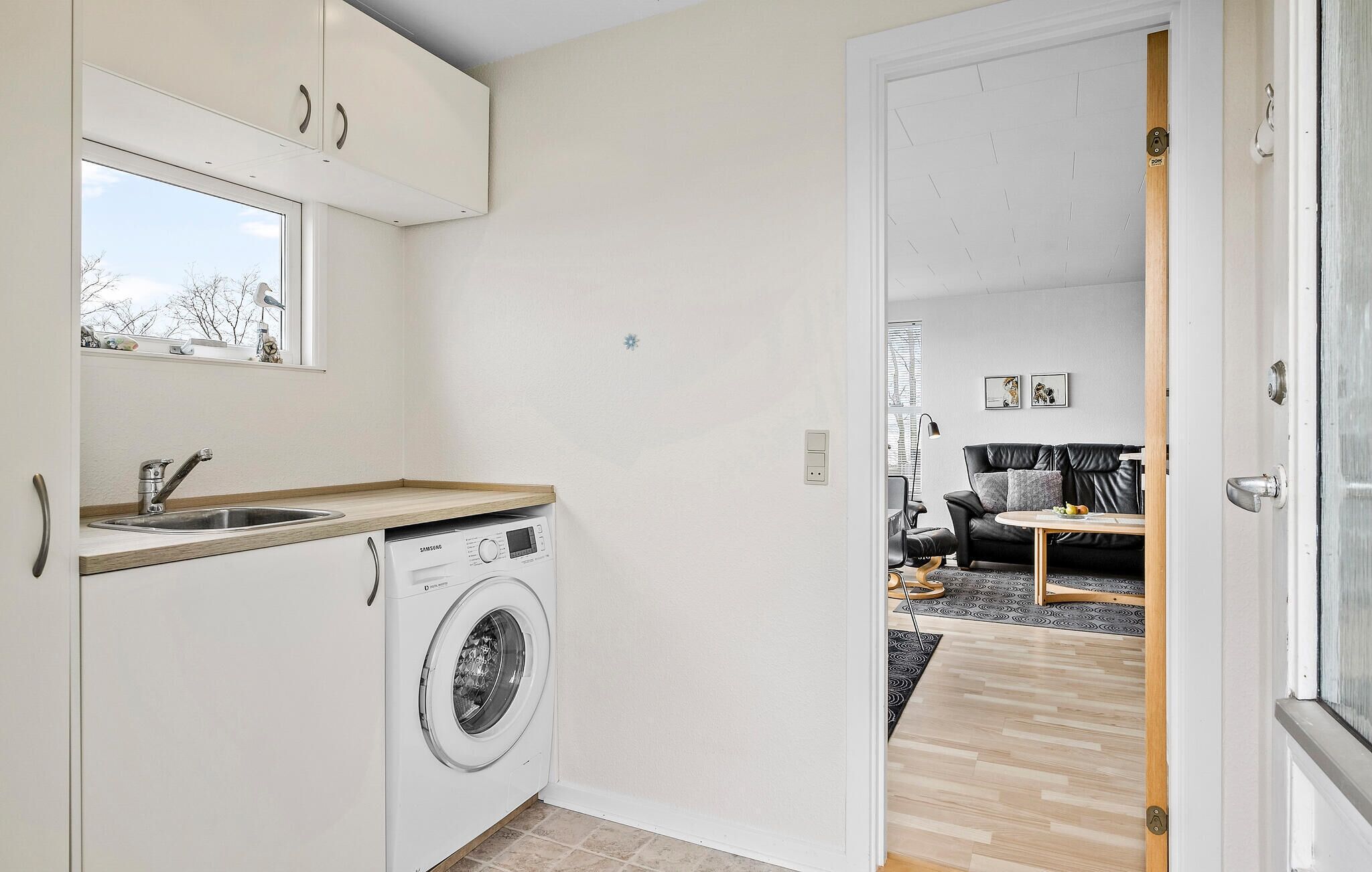 A compact kitchen with a washing machine, a sink, and a window.