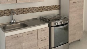 A modern kitchen with light wood cabinets, a stainless steel stove, and a herringbone tile backsplash. - «Javi's house: explore the charm of Cartagena (Cartagena de Indias)
