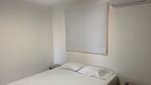 A bedroom with a bed, two bedside tables, and a wall-mounted air conditioning unit. - «Javi's house: explore the charm of Cartagena (Cartagena de Indias)