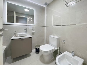 A modern bathroom with a sink, toilet, bidet, and bidet seat.