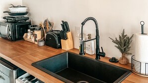 A kitchen with a black sink, wooden countertop, and various kitchen appliances. There are two signs on the wall, one reading "EAT" and another saying "GOOD FOOD GOOD MOOD". - Wild And Wonderful Silos (Harpers Ferry)