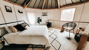 A cozy bedroom with a bed, a chair, a small table, and a window. - Wild And Wonderful Silos (Harpers Ferry)