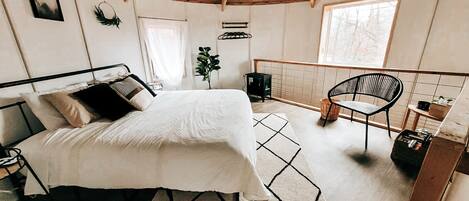 Une chambre confortable avec un lit, une chaise, une petite table et une fenêtre.