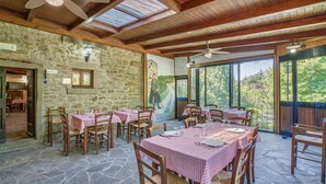 A restaurant with stone walls, wooden beams, and checkered tablecloths. Tables are set with cutlery and glasses.