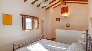 A bedroom with a bed, a window, a mirror, and a wall-mounted light fixture.