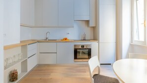 A modern kitchen with white cabinets, a wooden countertop, and a built-in oven.