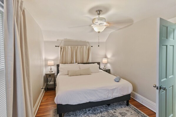 Une chambre à coucher avec un lit, des lampes de chevet, un ventilateur de plafond et une porte.