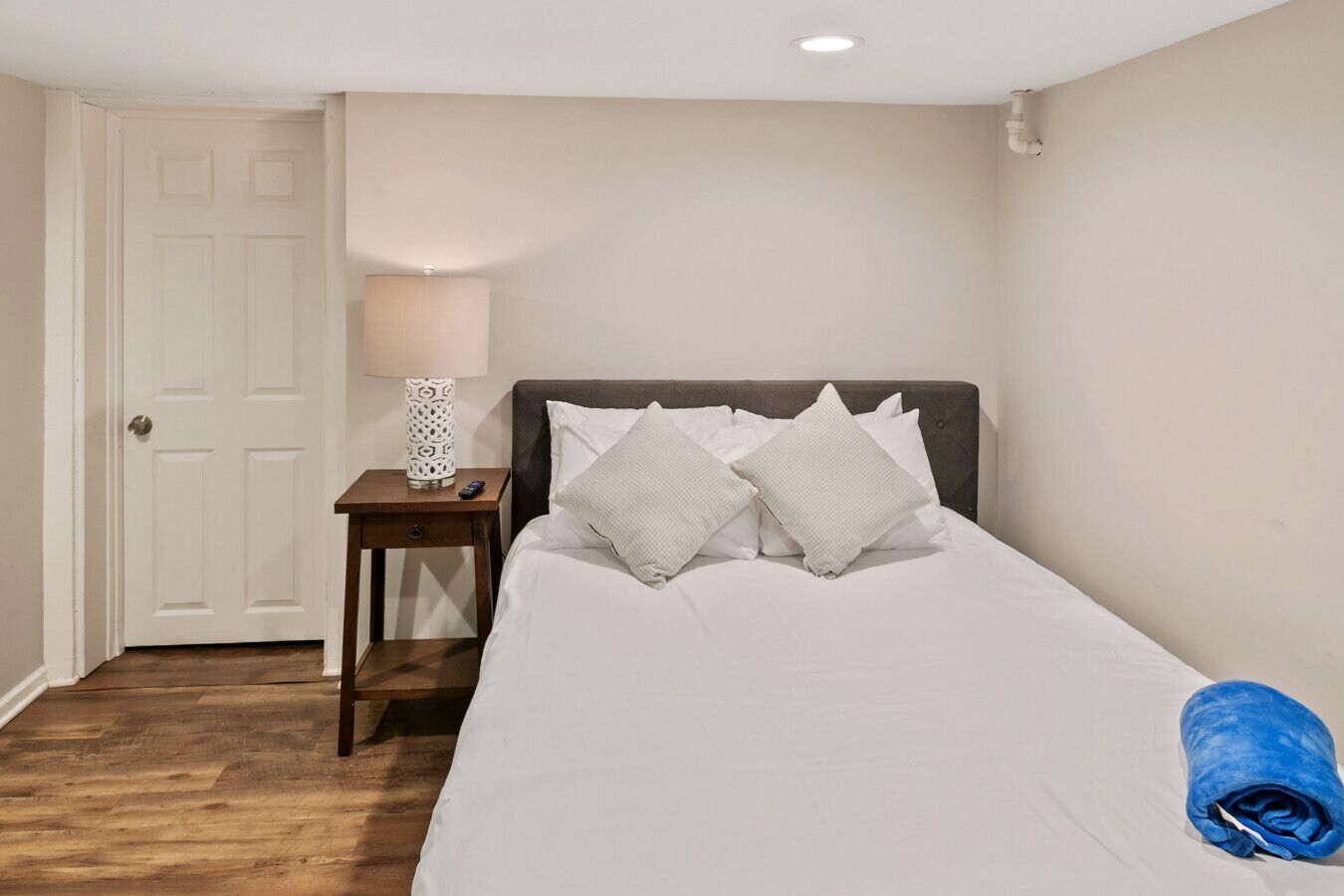 A bedroom with a bed, a nightstand, a lamp, and a door.