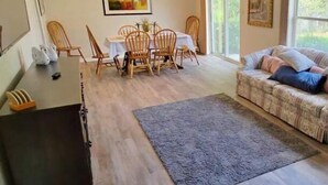 Un vaste espace de vie comprenant une table à manger, des chaises, un canapé et un ventilateur de plafond.