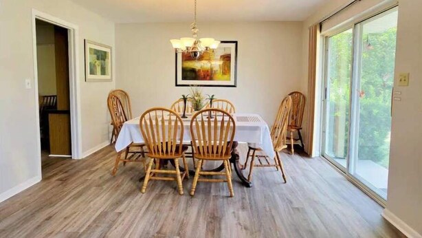 Un espace repas comprenant une table et des chaises, un lustre et une grande fenêtre donnant sur un beau paysage.
