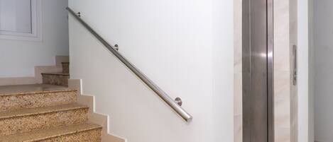 Un escalier avec une rampe, une porte et un interrupteur fixé au mur.