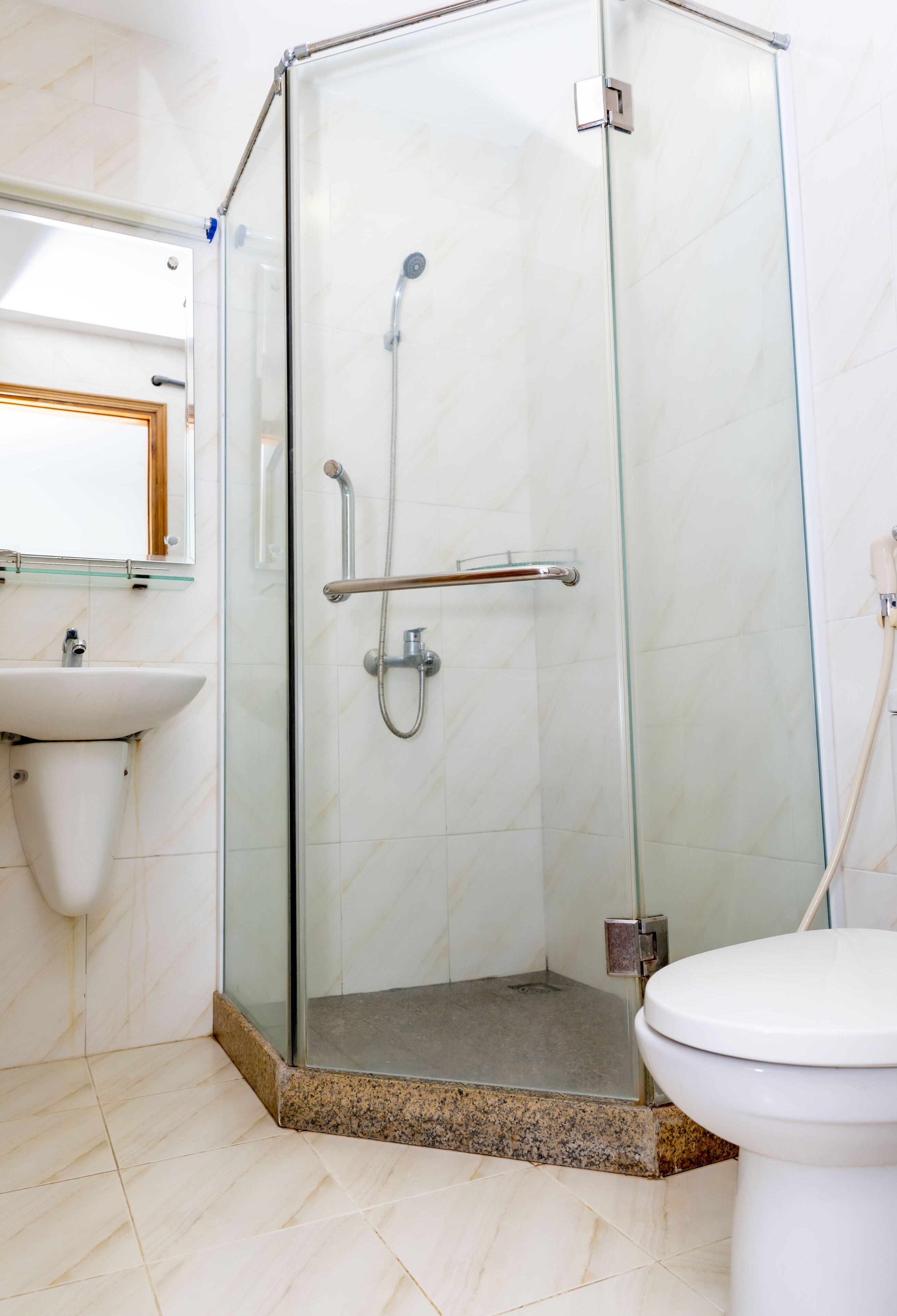 A bathroom with a glass-enclosed shower, a sink, and a toilet.