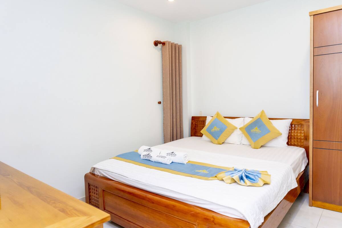 A neatly made bed with a white and blue bedspread, two matching pillows, and a wooden headboard.
