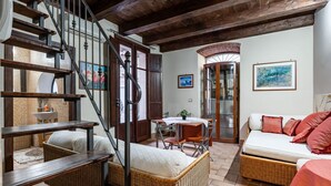 Amplia sala de estar con escaleras, muebles de mimbre, una mesa de comedor y un sofá.