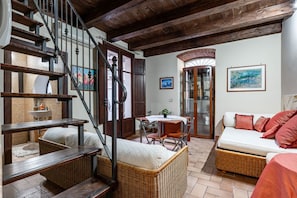 A spacious living area with a staircase, wicker furniture, a dining table, and a sofa.