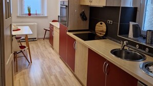 Una cocina moderna con armarios de madera, horno empotrado y un comedor con mesa y sillas.