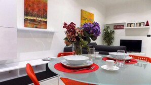 Een moderne eetruimte met een glazen tafel, rode stoelen, een vaas met bloemen en een 'NO SMOKING' bord aan de muur.