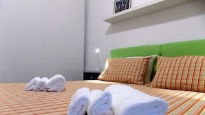 Een hotelkamer met een bed, kussens en opgerolde handdoeken.