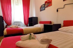 Hotelkamer met twee bedden, rode gordijnen, een radiator, een tv aan de muur en een poster.
