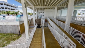 A covered wooden deck with white railings, leading to a building entrance.