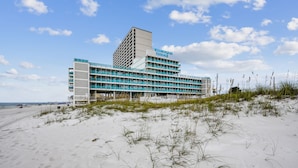 A hotel with multiple floors, a flat roof, and a beach view.