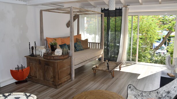Una habitación con una cama de madera, un aparador de madera, una mesita y vistas a la vegetación exterior.