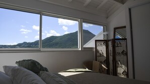 Un dormitorio con un ventanal grande, una cama, una silla y un biombo decorativo.