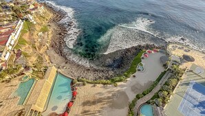 An aerial view of a coastal resort with a rocky shoreline, a swimming pool, and a tennis court. - LuxuryCorner-PrivateJacuzzi-LasOlasCondo-Rosarito (Playas de Rosarito)