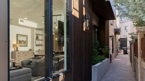 Un edificio moderno con ampie vetrate, rivestimento in legno e un vialetto che conduce a un cortile.