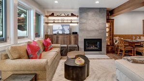 Una sala de estar acogedora con chimenea, un televisor grande y un comedor con muebles de madera.