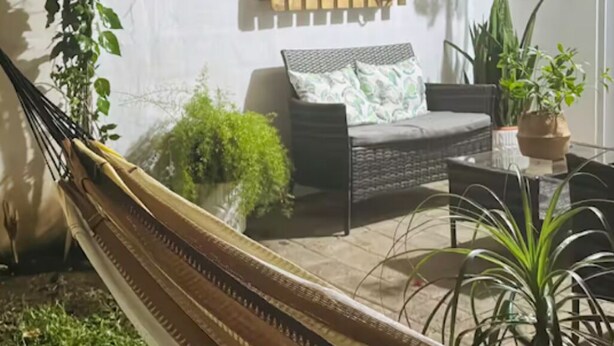 A hammock in a sunlit outdoor area with a sofa and potted plants. - Charming 2-bedroom house in Santa Ana with WiFi and AC (Santa Ana)