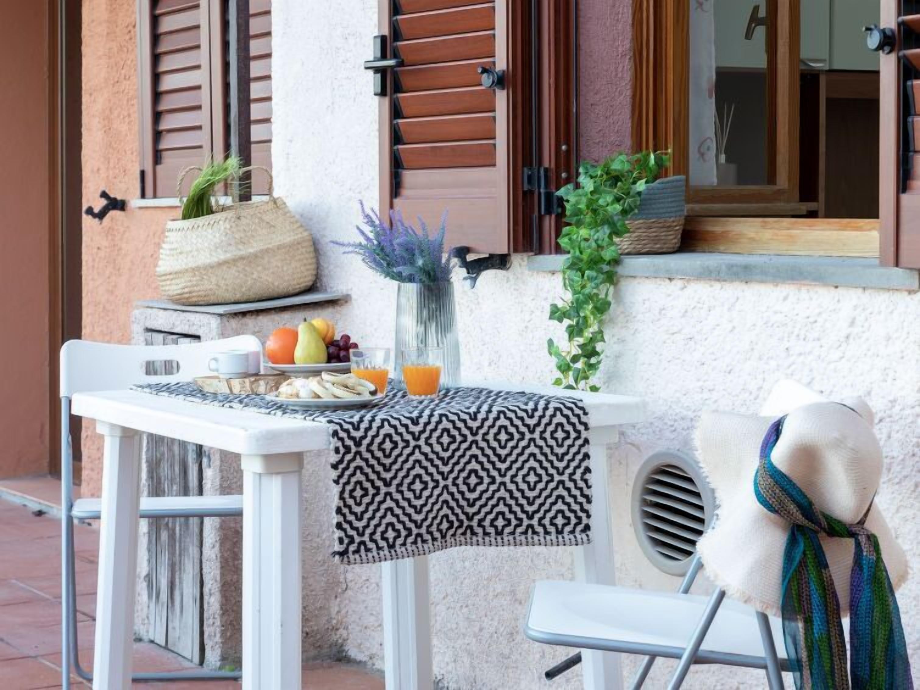 A small outdoor seating area with a table set for two, a chair, and a decorative plant.